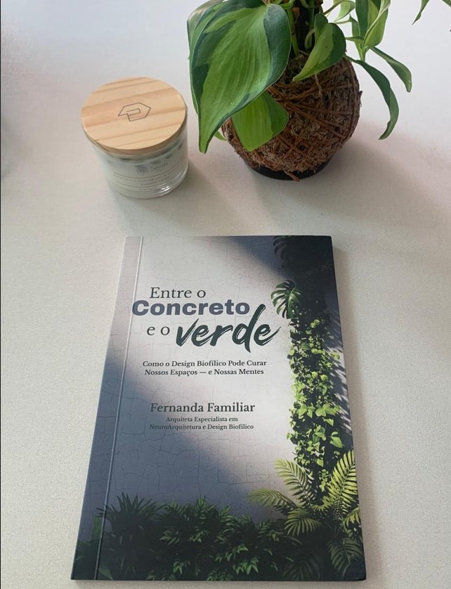 O livro sobre uma mesa clara, ao lado de uma vela e de uma planta em kokedama.